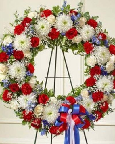 This beautiful red, white and blue wreath is a dignified expression of your feelings of love and care for a beloved veteran or patriot. Exquisitely crafted by our expert florists, it features the freshest red and white roses, blue delphinium and more accented by vibrant greenery creating an unforgettable tribute to honor their life. Appropriate for family, friends and business associates to send directly to the funeral home.