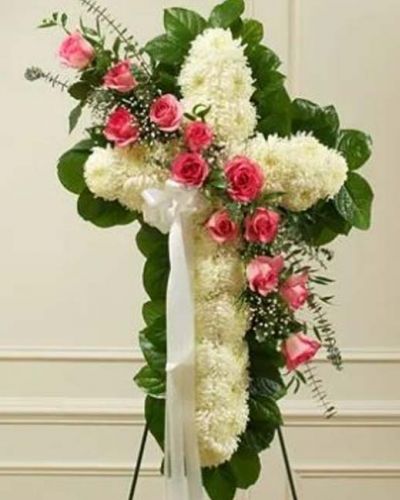 This beautiful floral tribute shows your faith, hope and love during this difficult time. The standing spray arrangement in the shape of a cross is created from fresh white mums, pink roses, spiral eucalyptus and more. Traditionally sent directly to the funeral home by family members or friends and displayed on a stand.