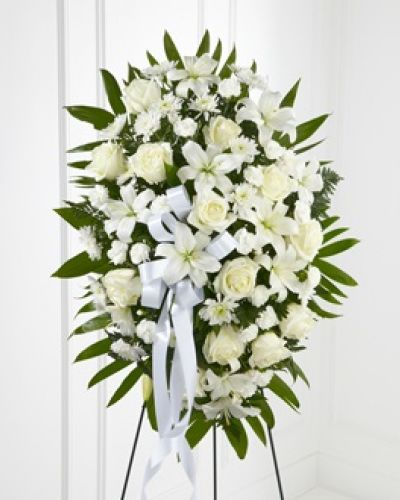 The FTD® Exquisite Tribute™ Standing Spray is an elegant display of sweet serenity. White roses, Asiatic lilies, chrysanthemums and mini carnations are artfully arranged amongst emerald palm fronds and lush greens. Accented by white satin ribbon and standing on a wire easel, this standing spray is an outstanding way to honor the life of your loved one.
